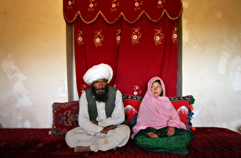 Faiz Mohammed, 40, and Ghulam Haider, 11, sit in her home prior to their wedding in the rural Damarda Village, Afghnanistan on Sept. 11, 2005.  Ghulam said she is sad to be getting engaged as she wanted to be a teacher. Her favorite class was Dari, the local language, before she was made to drop out of school. Married girls are seldom found in school, limiting their economic and social opportunities. Parents sometimes remove their daughters from school to protect them from the possibility of sexual activity outside of wedlock. It is hard to say exactly how many young marriages take place, but according to the Afghan women's ministry and women's NGOs, approximately 57 percent of Afghan girls get married before the legal age of 16. In addition, once the girl's father has agreed to the engagement, she is pulled out of school immediately. Early pregnancies also result in an increase in complications during child birth. © Stephanie Sinclair / VII
