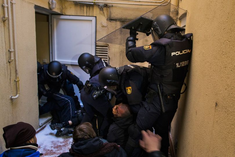 Riot police grab the face of an activist as they remove housing right activists who tried to stop Umberto Jimenez's eviction in Madrid, Spain, Monday, Feb. 9, 2015. Umberto Jimenez, 46 years old, lost his foreclosed apartment to a moneylender after he could not afford to pay his debt due to his financial situation. He borrowed euro 4,000 ($4,510) after he lost his job as a security guard but six months after his debt reached euro 32,000 ($ 36,1000). Umberto and his son got evicted despite housing right activists' confrontion with police, where many of them got injured. (AP Photo/Andres Kudacki)