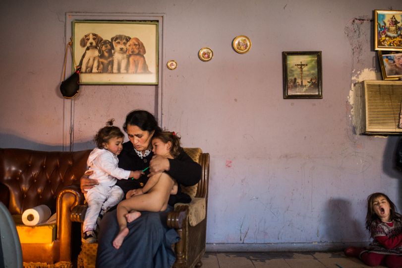 Maria Jesus Navarro, 48 years old holds her grand children as they warms up next to the electric heat in the suburbs of Madrid, Spain, Monday, Dec. 30, 2013, as Navarro's family waits to be evicted from the home they have lived in for the past ten years. The Navarro's are one of the thirteen families in the area who live in impoverished conditions and whose future is still uncertain as their evictions are currently on hold. The families believe the Madrid City Hall is trying to evict them to make way for a road construction project and feel the city should offer them alternative housing.
