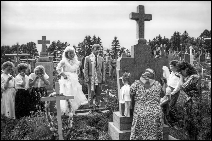 1991, Ukraine --- Roman and Luba visit her father's grave before their wedding ceremony to honor his memory.Members of the wedding party accompany them. --- Image by © David Turnley/Corbis
