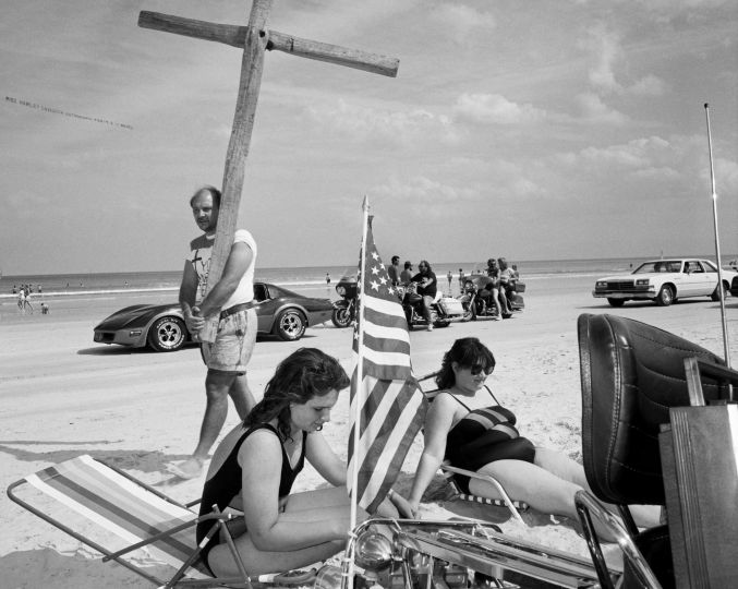 © Carl De Keyzer - Magnum
Caption/Description: USA. Daytona Beach.
Bike Week - 50th anniversary (app. 400.000 bikers in a small town).Preacher with wooden cross on the beach highway.
