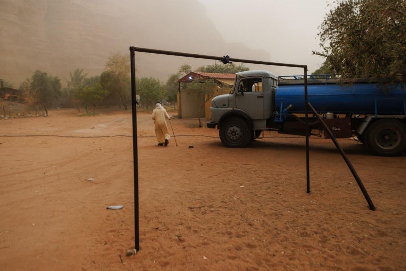 © Annie Sakkab - Against the backdrop of a swirling sandstorm in the Wadi Rum desert, 71-year-old Mohammad Al Zawaideh of Disi village navigates the increasingly harsh landscape of southern Jordan, a region defined by a stark paradox: It sits atop the massive Disi Aquifer, a 30,000-year-old ‘fossil’ water resource shared with Saudi Arabia, of which only 1% lies within Jordan, yet its people face acute water scarcity and the accelerating impacts of climate change. While this non-renewable sandstone reservoir serves as a strategic lifeline for the nation, supplying 100 million cubic meters of high-quality water annually to Amman via a 325-km pipeline, the local community watches as their water table drops by over 80 cm each year due to heavy extraction and minimal modern recharge.